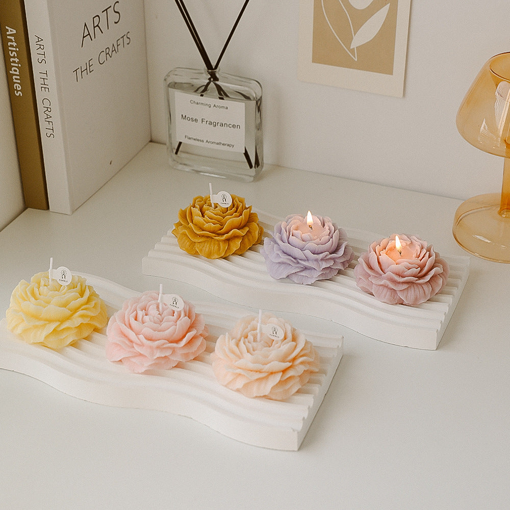 Rosenförmige Duftkerzen in Pastellfarben auf Deko-Tablett