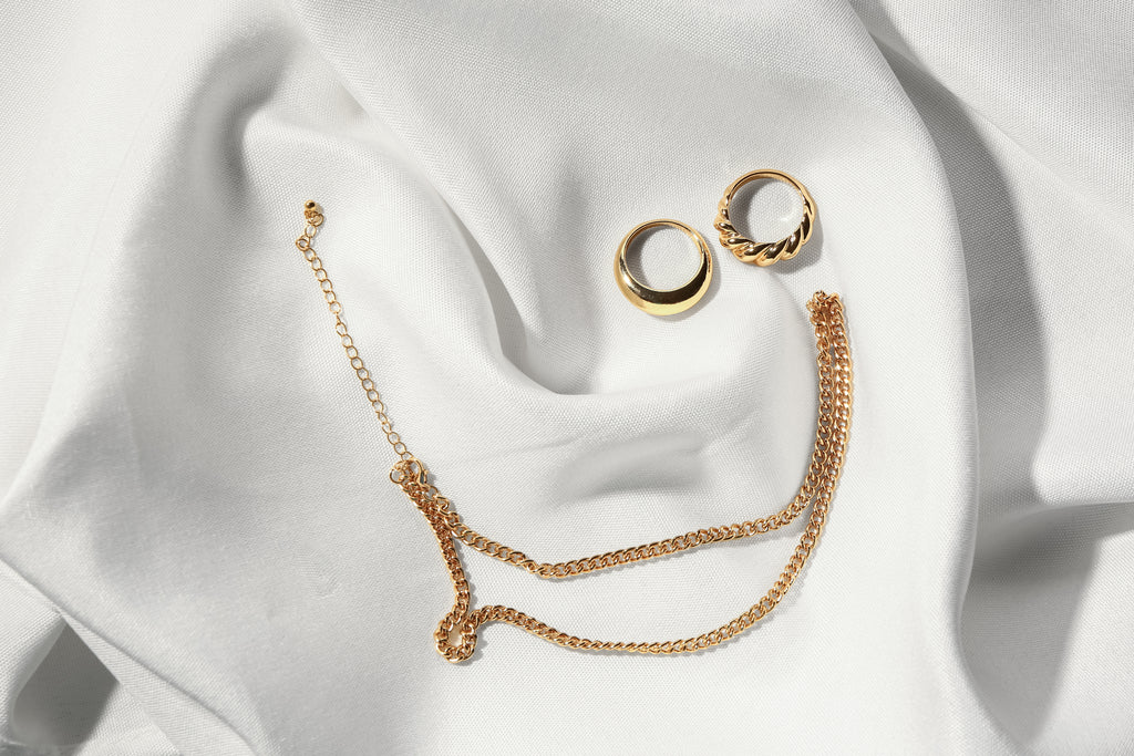 Gold necklace and rings on white background
